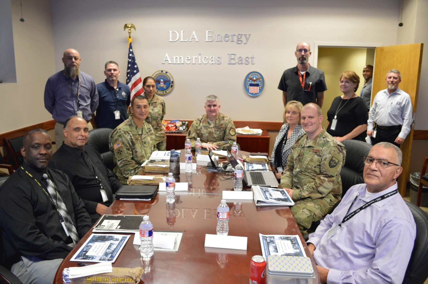 military and civilian personnel sit around a table