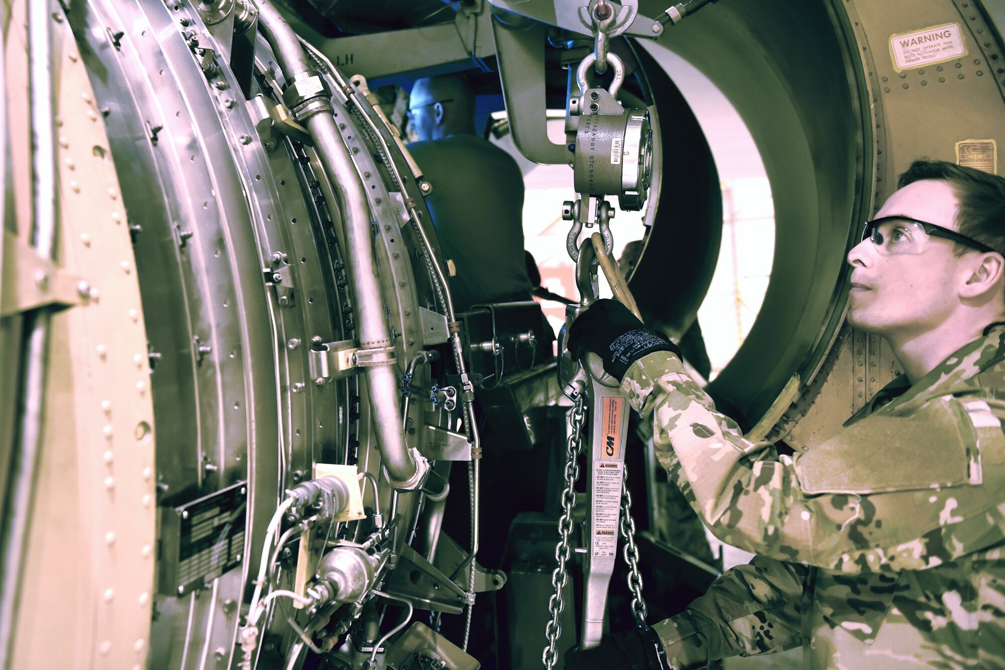 Senior Airman Jesse Medrano, 434th Maintenance Squadron propulsion specialist, uses a chain hoist to raise an engine into place on a KC-135R Stratotanker at Grissom Air Reserve Base, Indiana, Jan. 11, 2020. The 6,000 pound engine replaced another engine that showed signs of over temping and decreased performance. (U.S. Air Force photo/Tech. Sgt. Jami Lancette)