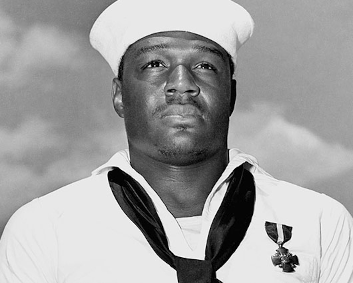 Black and white photo of African American Sailor in dress whites uniform.