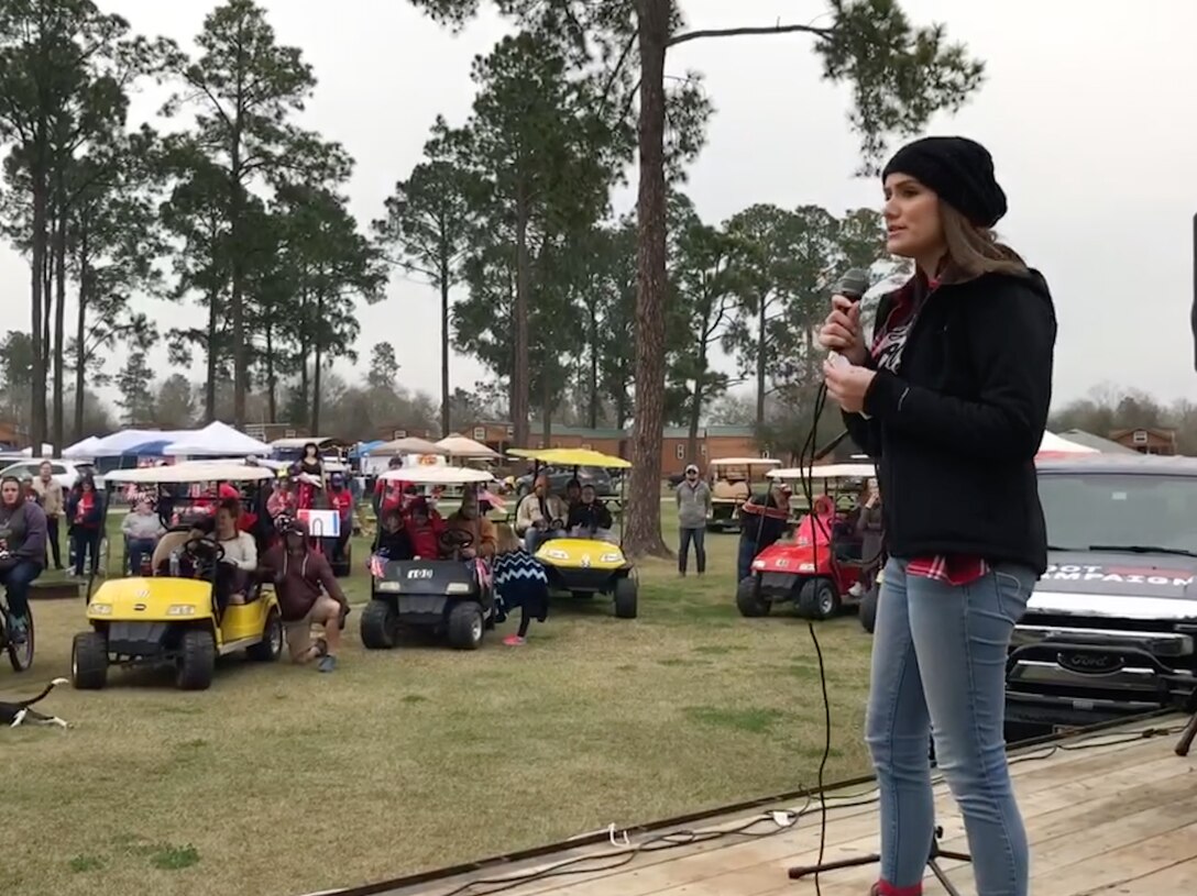 Photo of Johnson speaking on stage to a large outdoor gathering.