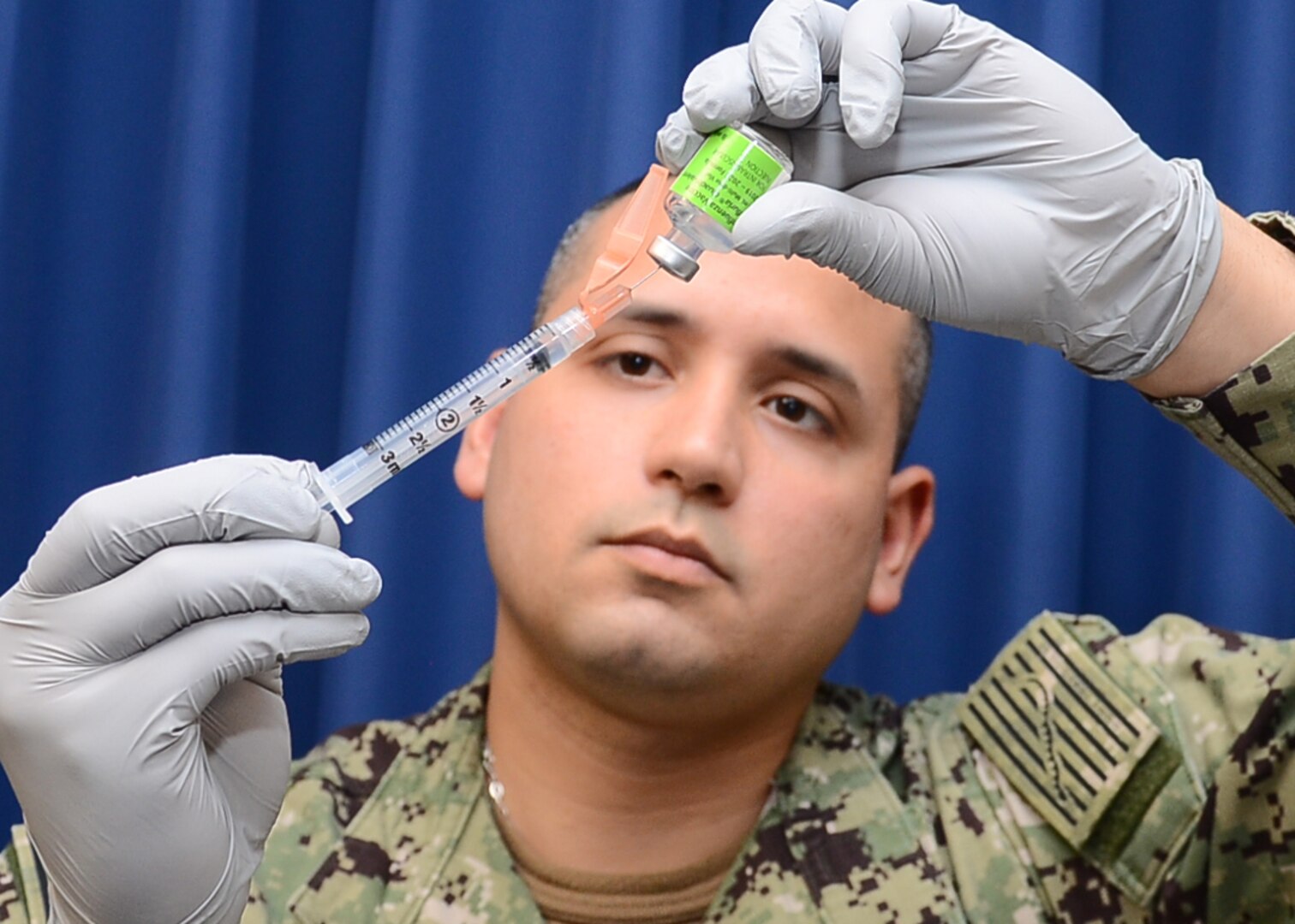 Navy Retail Services Specialist 2nd Class Tomas Vasquez prepares a syringe with the influenza vaccine before administering annual Flu Shots at Naval Health Clinic Corpus Christi.