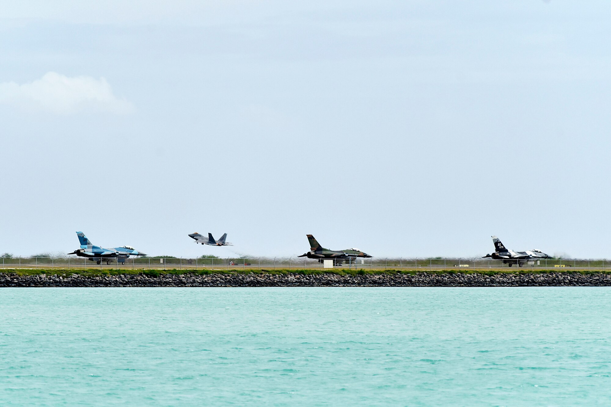 Three F-16 Fighting Falcons assigned to the 18th Aggressor Squadron taxi down the runway while an F-22 Raptor assigned to the Hawaii Air National Guard takes off during Sentry Aloha 20-1 at Joint Base Pearl Harbor-Hickam, Hawaii, Jan. 15, 2020. The 18th AGRS uses mobile training teams to increase U.S. Air Force, Air National Guard and joint partner nations’ lethality and readiness. (U.S. Air Force photo by Senior Airman Beaux Hebert)