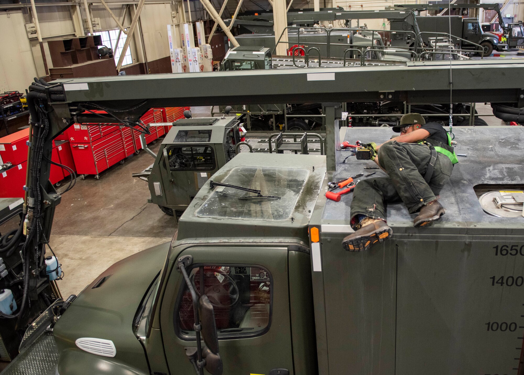 Jessie Mauldin, 673d Logistics Readiness Squadron heavy mobile equipment mechanic, drills a hole for an eyelet on top of a deicing truck to tether a fall-protection safety harness at Joint Base Elmendorf-Richardson, Alaska, Jan. 22, 2019. The modification involves strategically attaching four eyelets to the top of each truck so mechanics can attach a mobile safety harness. Mauldin has taken steps to push his innovation to all heavy mobile equipment maintenance shops Air Force-wide.