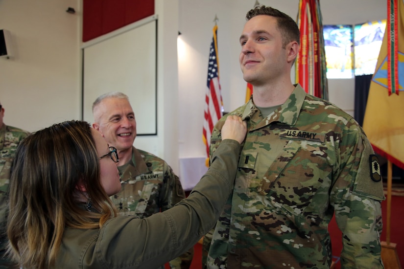 Newly appointed U.S. Army Reserve Chaplain (1st Lt.) Gabriel Pech, 7th Mission Support Command, receives the Army Chaplain cross from his wife, Hannah, while the U.S. Army Chief of Chaplains, Chaplain (Maj. Gen.) Thomas L. Solhjem looks on, during a pinning ceremony held at the Daenner Kaserne Chapel in Kaiserslautern, Germany on January 22, 2020. Pech was the first U.S. Army Reserve officer to complete the Chaplain Candidate Program in Europe.