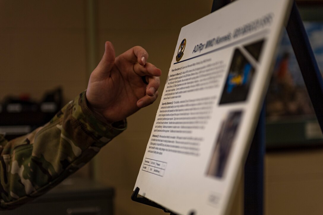 A photo of an Airman pointing to a poster