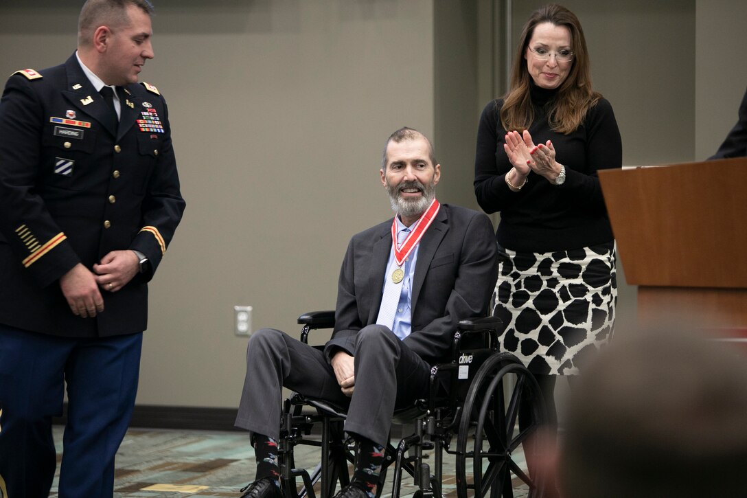 Alex Baylot is applauded by his wife, Paula, and LTC Michael Harding after receiving the Bronze Order of the de Fleury Medal.