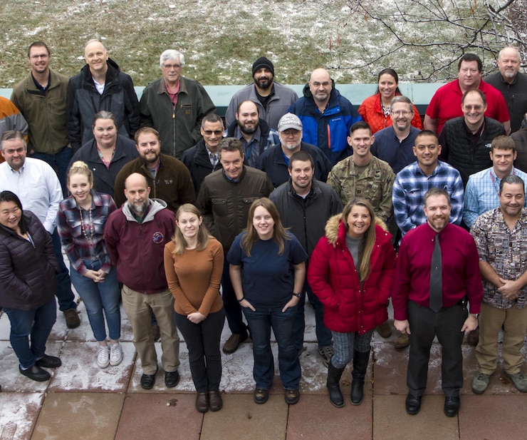 photo of a group of engineers standing on a balcony, looking up at the camera