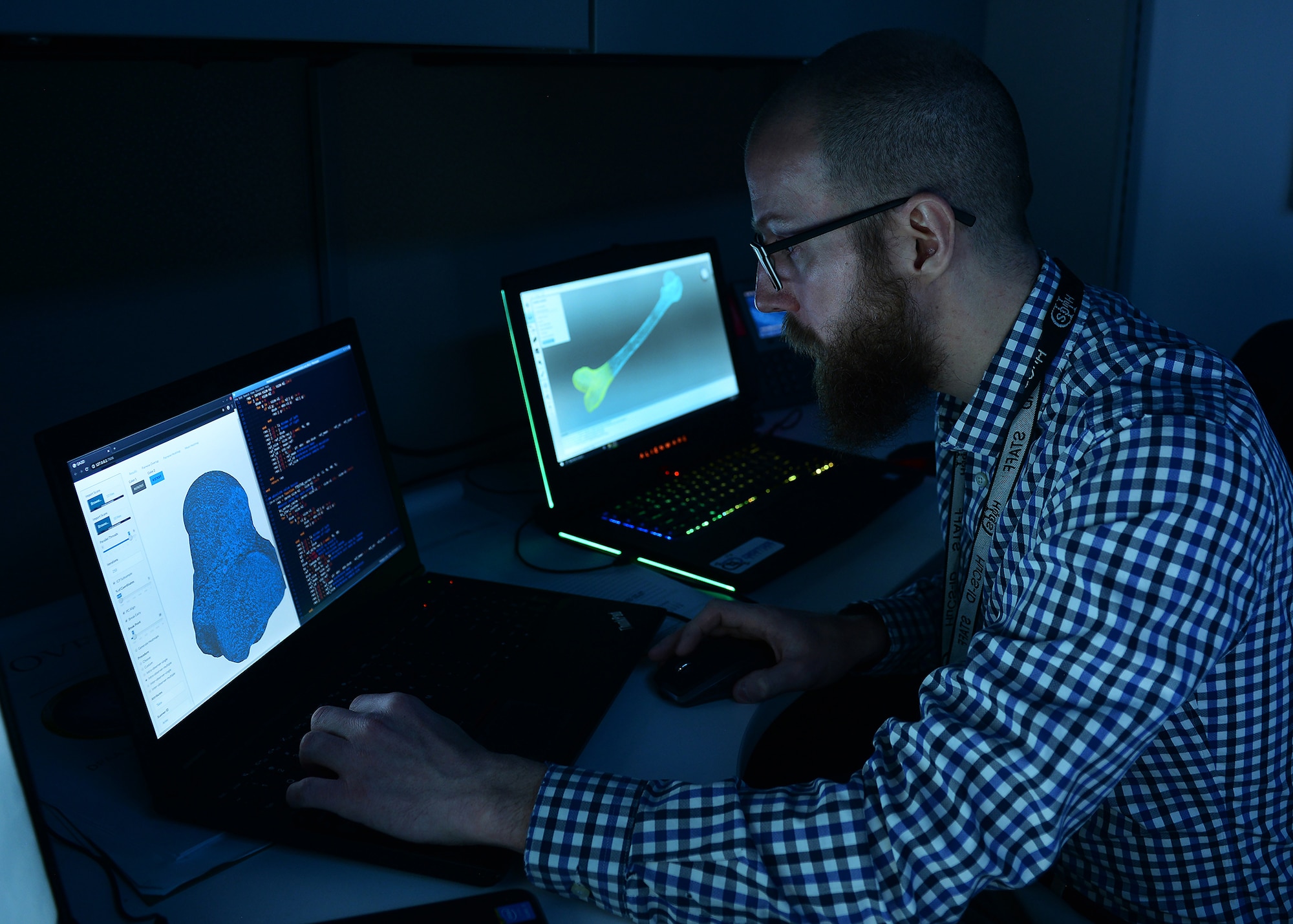 A lab technician works on computer screens creating a 3-D model of skeletal remains.