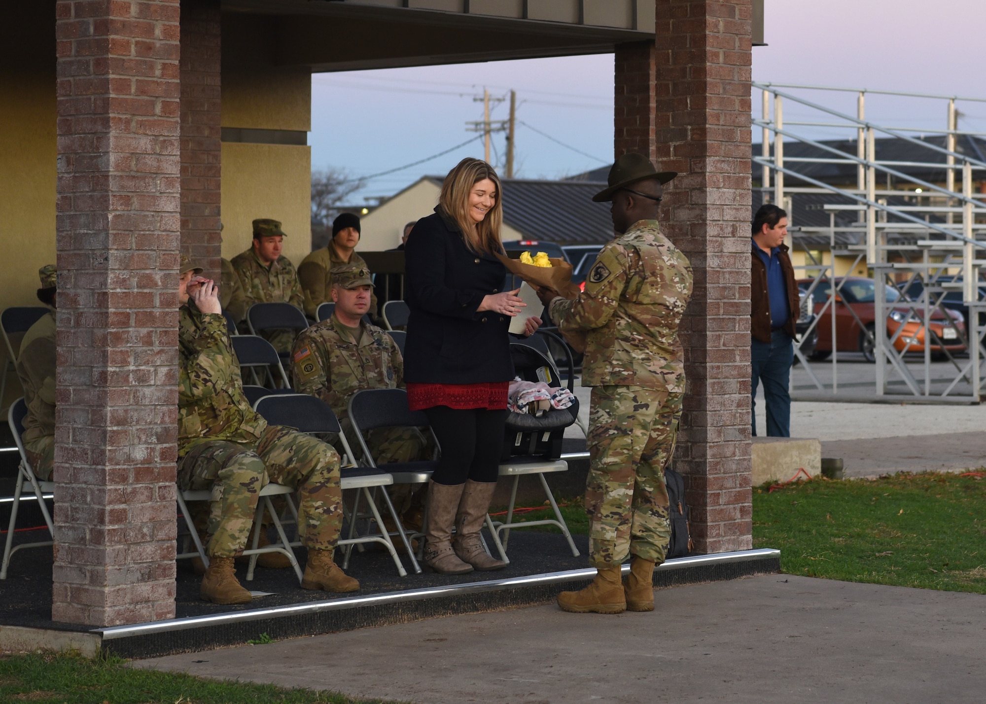 U.S. Army Staff Sgt. Damont Foxx, 344th Military Intelligence Battalion drill sergeant, welcomes Mrs. Leanne Sauls, spouse of the incoming 344th MI BN Charlie company commander, Capt. Nicholas Sauls, with a bouquet of yellow roses at the Activation Ceremony and Assumption of Command of the Charlie Company on the parade field at Goodfellow Air Force Base, Texas, Jan. 24, 2019.  Yellow is the color of new beginnings and symbolizes her arrival to the 344th MI BN Charlie Company family.  (U.S. Air Force photo by Airman 1st Class Abbey Rieves)