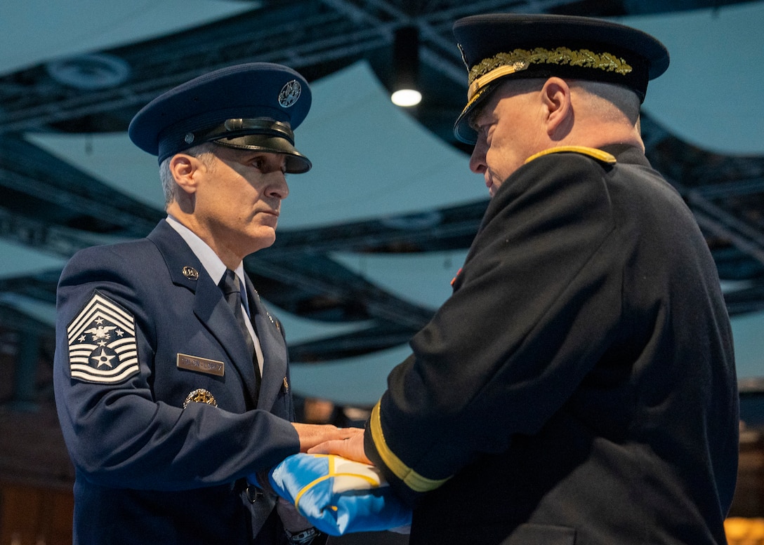 Soldier presents flag to airman.