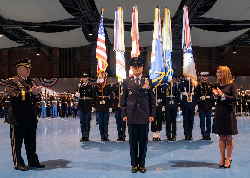 Man stands in front of national, service flags.