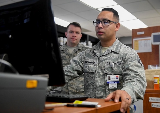 Staff Sgt. Pablo Santamaria, right, a pharmacy technician assigned to the 628th Medical Support Squadron, and Tech. Sgt. Albert Lepine, left, 628th Medical Support Squadron NCO in charge of pharmacy services, learn the ScriptCenter program to load prescriptions into the ScriptCenter machine in the 628th Medical Group Pharmacy, January 21, 2020, at Joint Base Charleston.