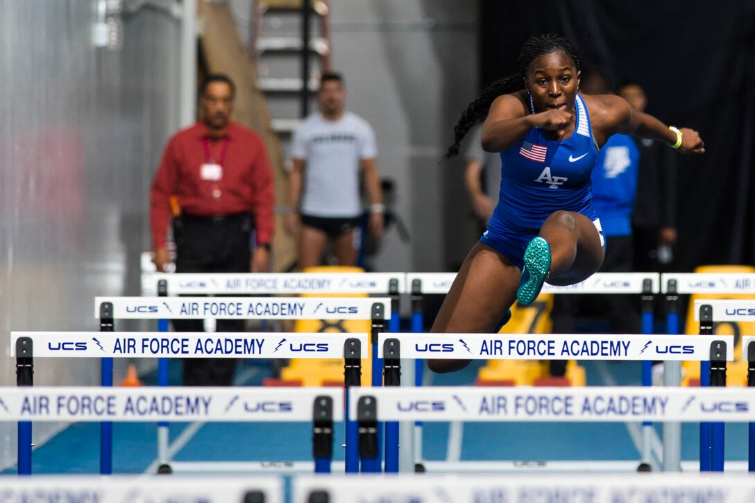 An Air Force cadet jumps over a hurdle.