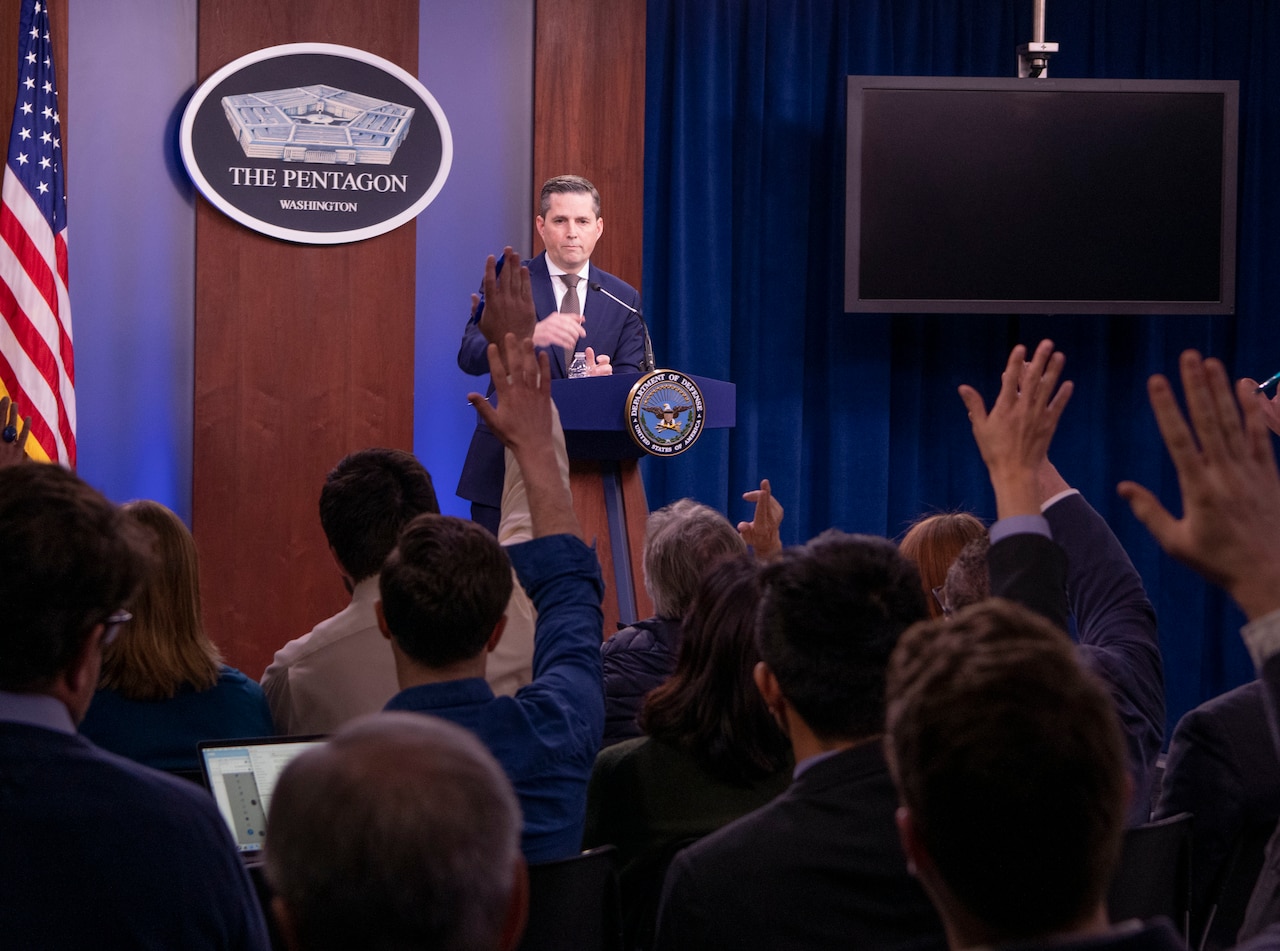 Man stands behind podium and speaks into microphone.