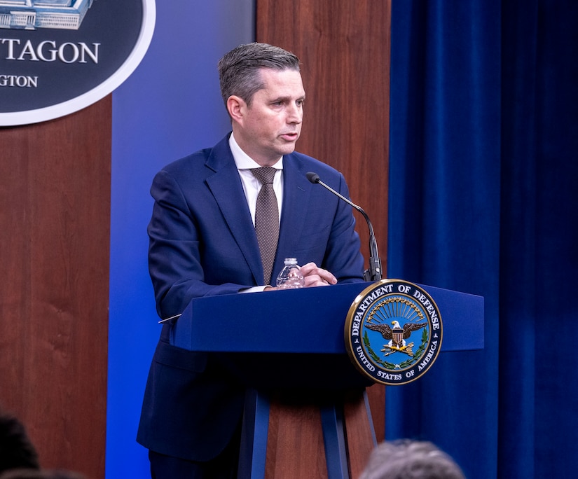 Man stands behind podium and speaks into microphone.