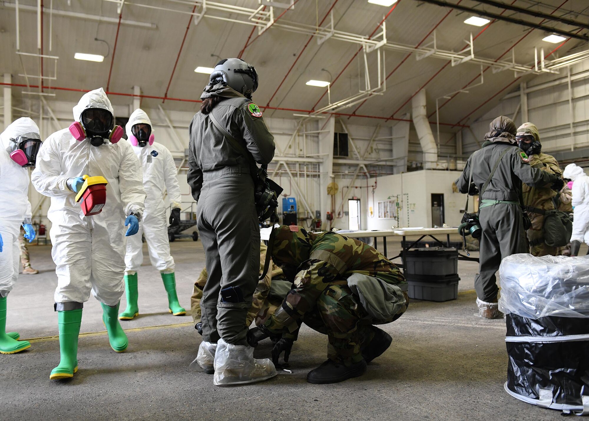 Multiple Airmen check another Airmen for simulated radiation with equipment.