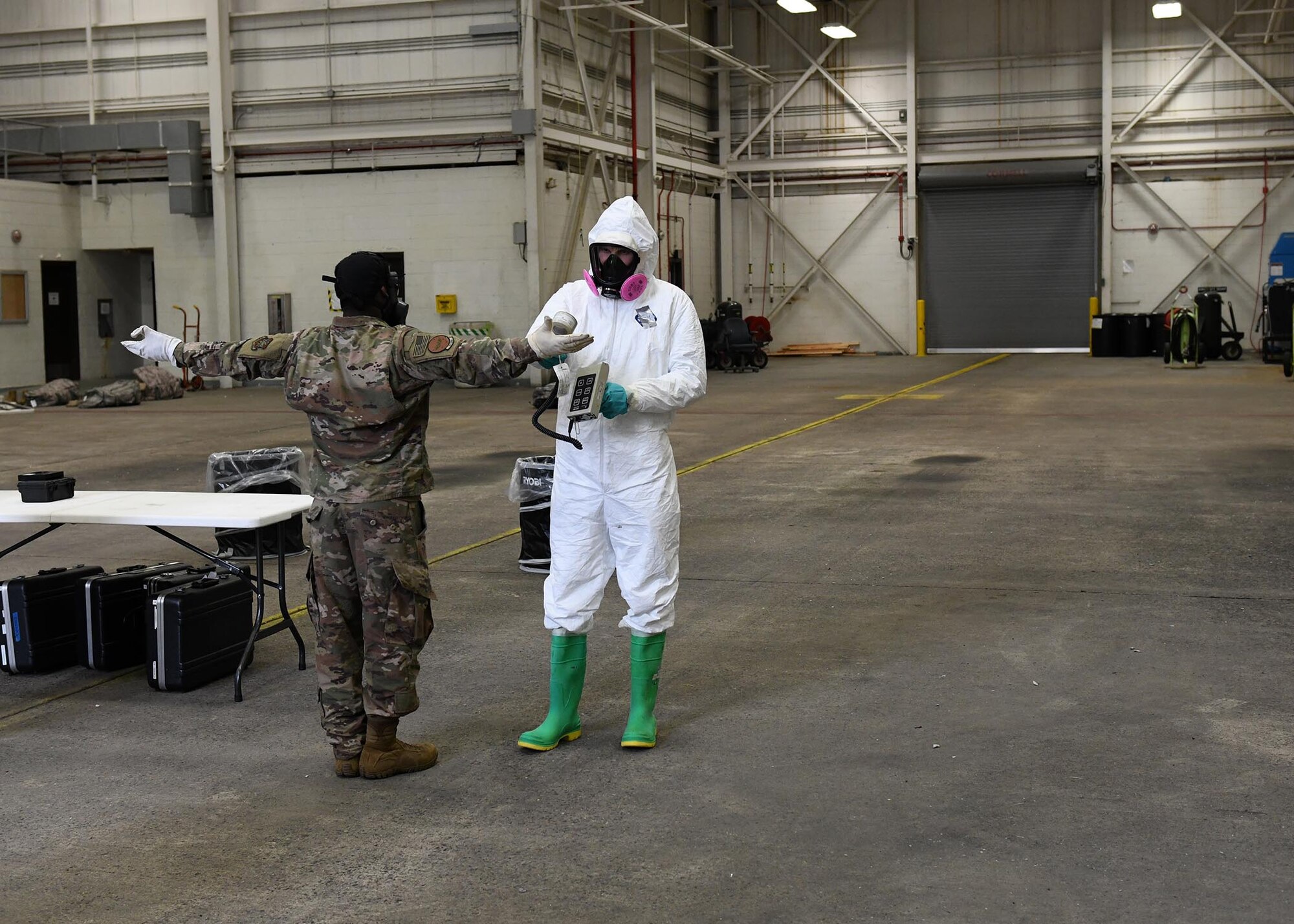 An Airman checks another Airman for simulated radiation with a small grey tool.