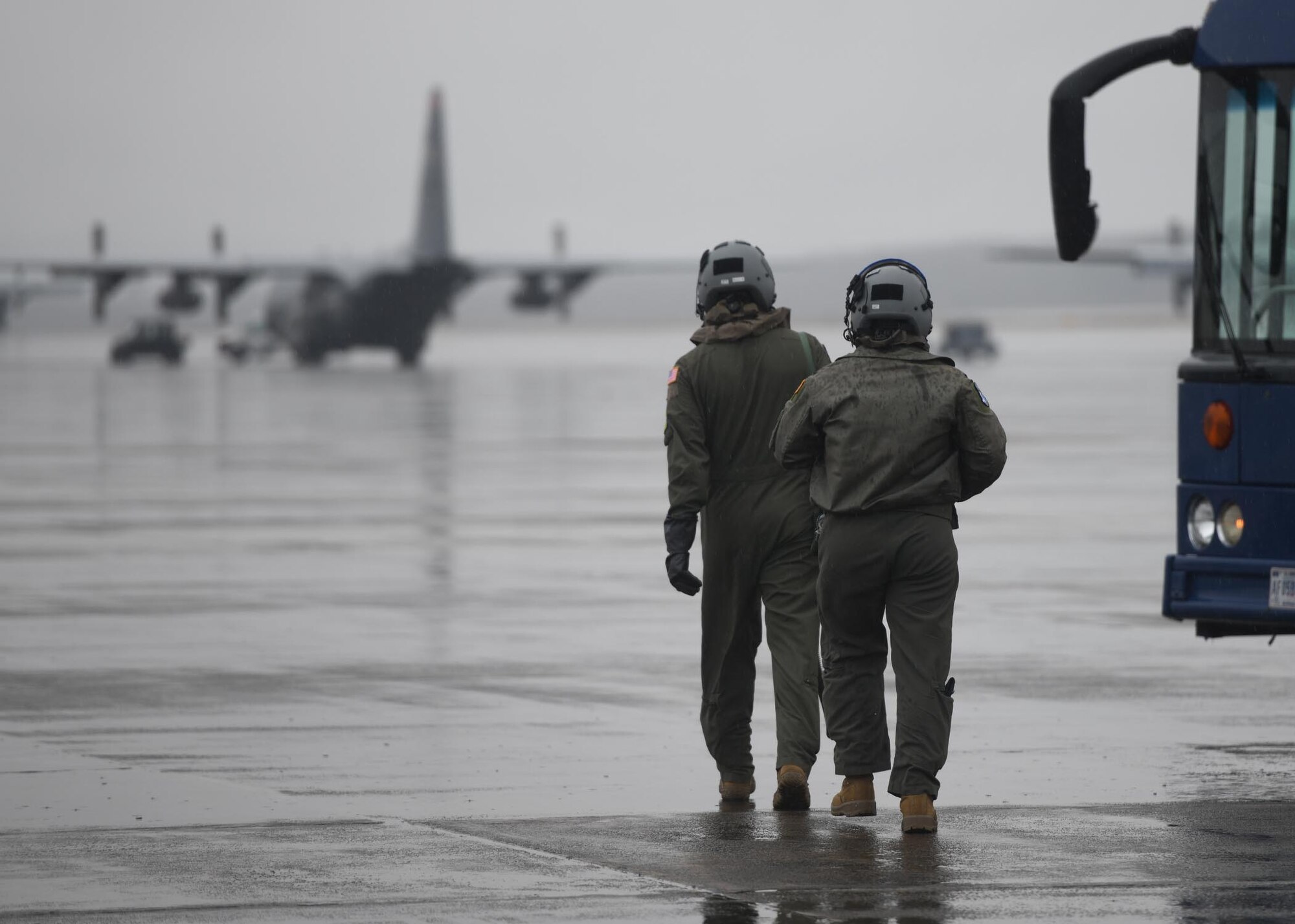 Two Airmen walk towards a bus.