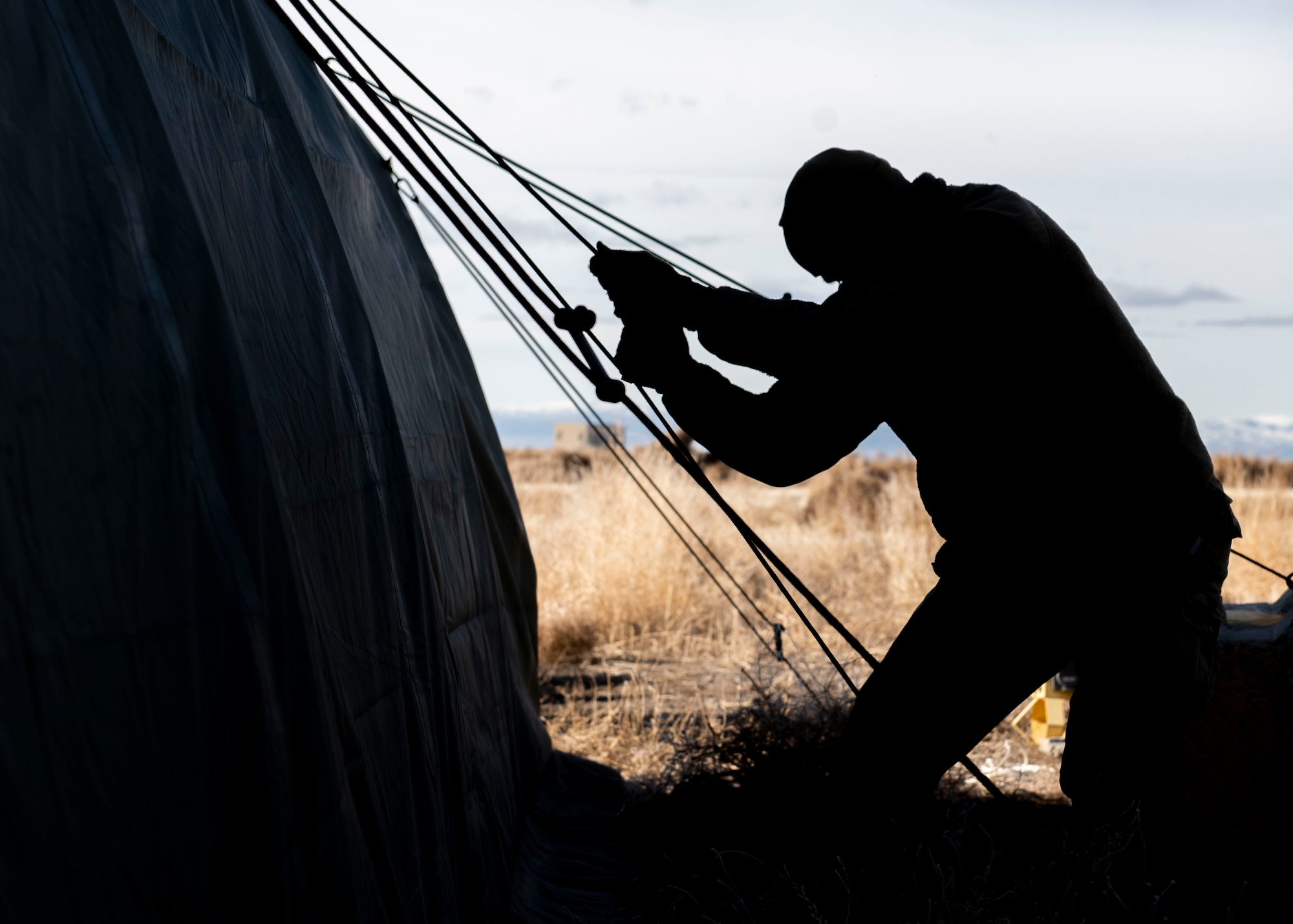 An Airman from the Civil Engineer Squadron hoists a tent grounding line during the Base Emergency Engineer Force training, Jan. 23, 2020, at Mountain Home Air Force Base, Idaho. This training was conducted to equip Airman with skills from other career fields to enhance their readiness. (U.S. Air Force photo by Senior Airman Tyrell Hall)