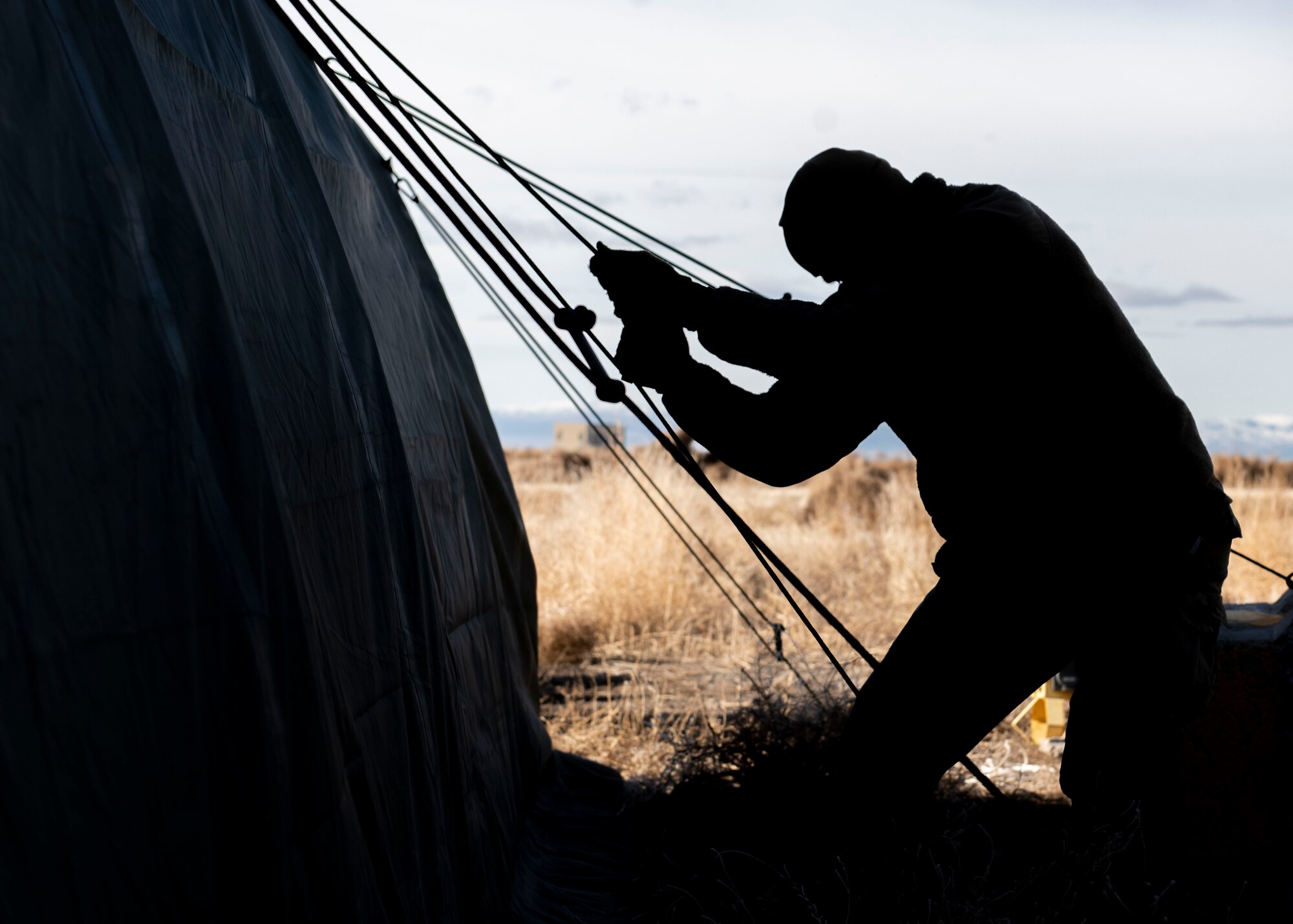 An Airman from the Civil Engineer Squadron hoists a tent grounding line during the Base Emergency Engineer Force training, Jan. 23, 2020, at Mountain Home Air Force Base, Idaho. This training was conducted to equip Airman with skills from other career fields to enhance their readiness. (U.S. Air Force photo by Senior Airman Tyrell Hall)