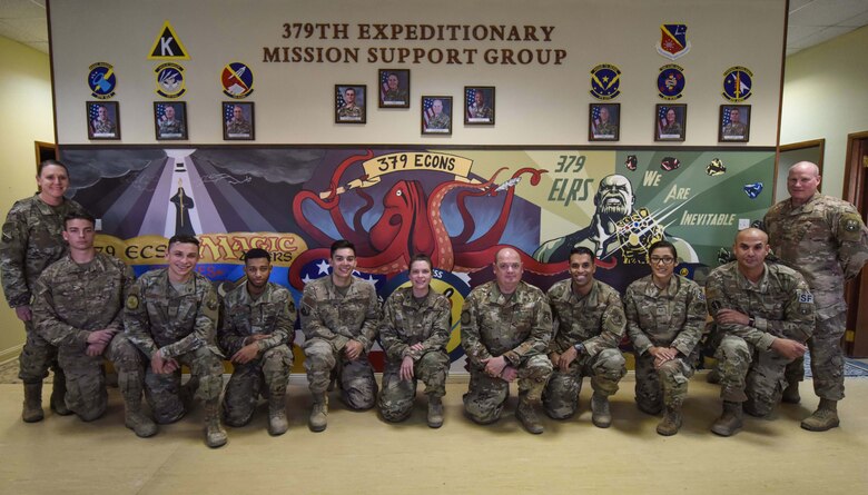 379th Expeditionary Mission Support Group leadership stands alongside mural artists at Al Udeid Air Base, Qatar on Dec. 5, 2019. The mural took 250 hours of volunteering to be completed and many of the Airmen did not know each other prior to creating the artwork. (U.S. Air Force photo by Senior Airman Shay Stuart)