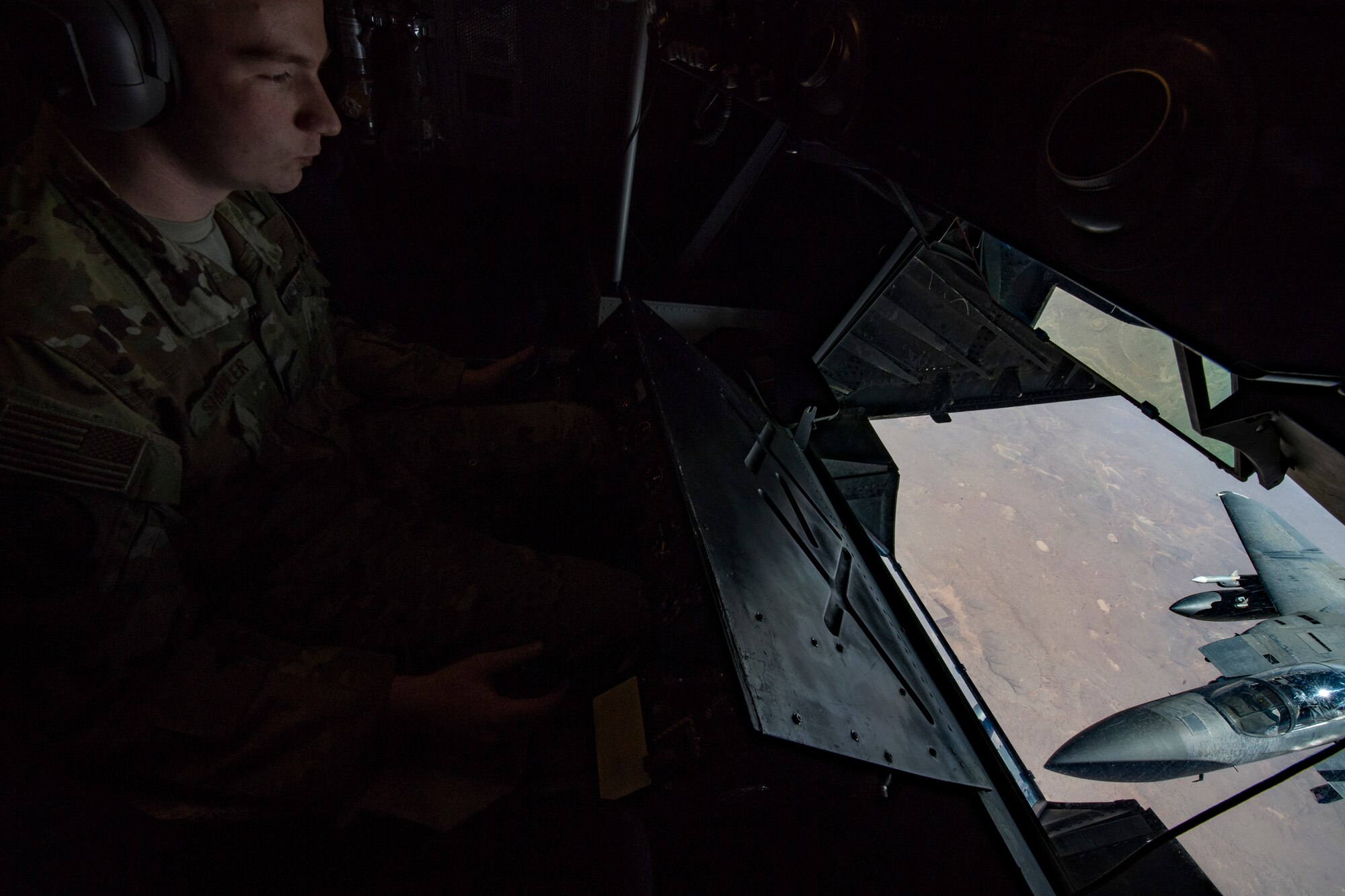 A U.S. Air Force KC-10 Extender in-flight refueling specialist with the 908th Expeditionary Air Refueling Squadron, deployed to Al Dhafra Air Base, United Arab Emirates, conducts an aerial refueling with an F-15E Strike Eagle assigned to the 494th Expeditionary Fighter Squadron above the U.S. Central Command area of responsibility, Jan. 13, 2020.