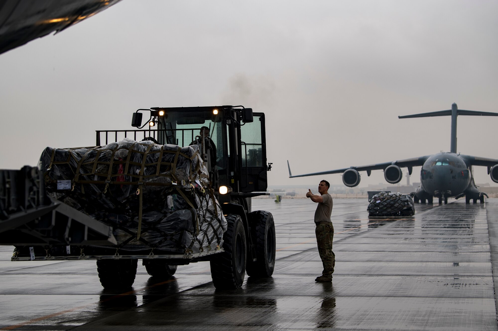 A U.S. Air Force loadmaster assigned to the 816th Expeditionary Airlift Squadron, right, guides a U.S. Air Force aerial porter assigned to the 746th Expeditionary Logistics Readiness Squadron transporting cargo to a U.S. Air Force C-17 Globemaster III at Al Udeid Air Base, Qatar, Jan. 10, 2020.