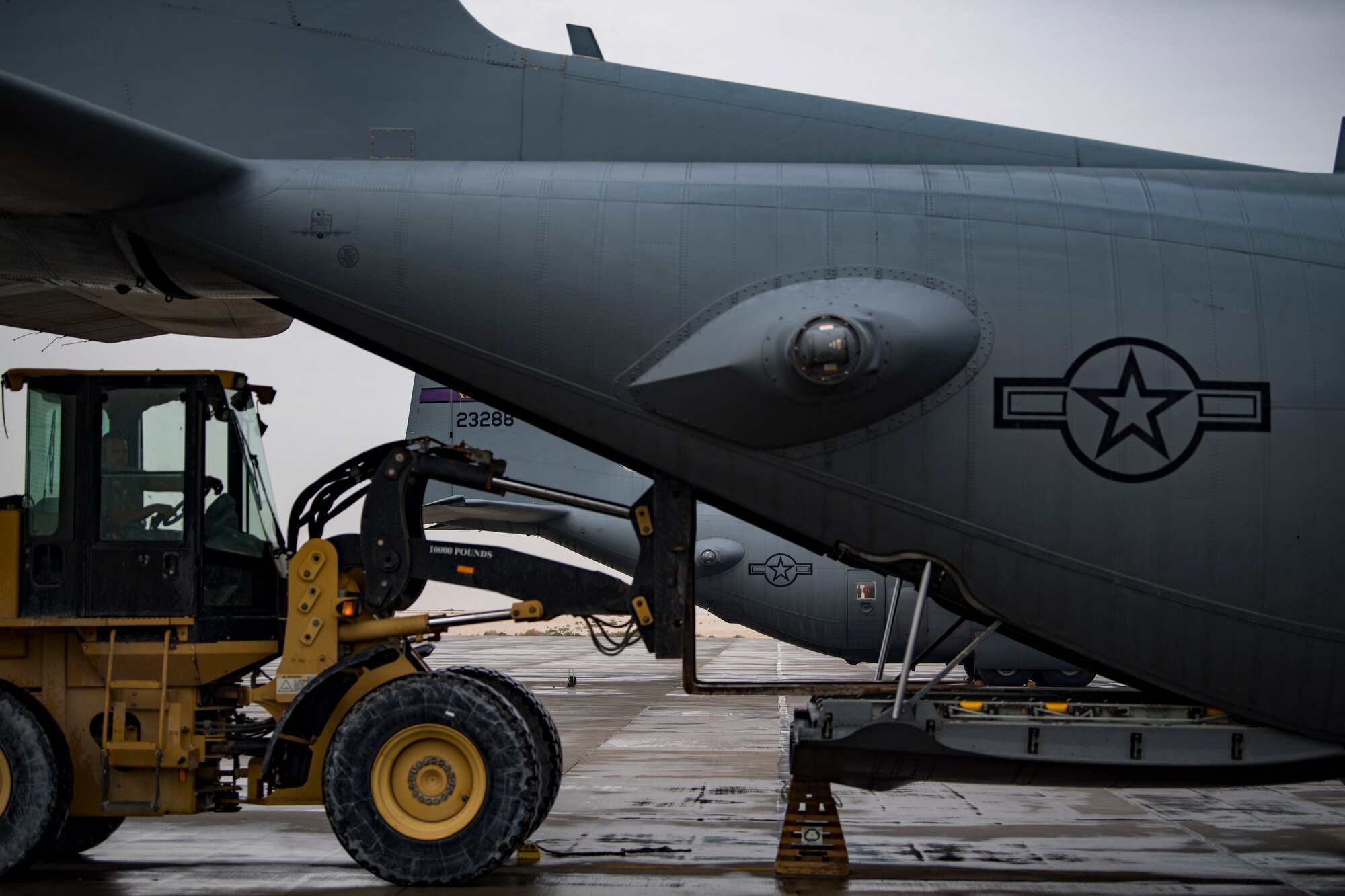 A U.S. Air Force aerial porter assigned to the 746th Expeditionary Logistics Readiness Squadron brings cargo to the ramp of a U.S. Air Force C-130 Hercules assigned to the 746th Expeditionary Airlift Squadron at Al Udeid Air Base, Qatar, Dec. 15, 2019.