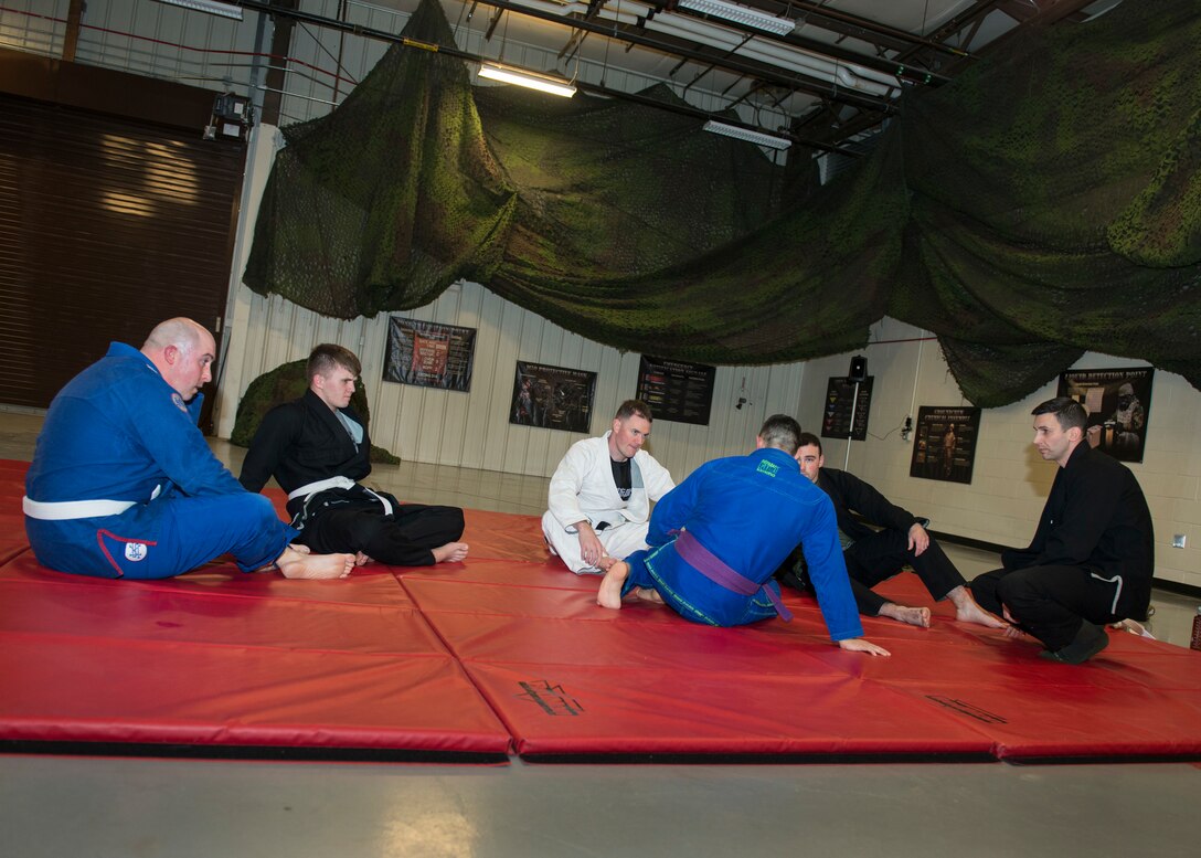 Master Sgt. Ian McMahon (front-center), 103rd Security Forces Squadron flight chief and combatives instructor, instructs a group of squadron members during an informal jiu-jitsu session at Bradley Air National Guard Base, East Granby, Conn. Jan. 23, 2020. The group of Security Forces members meets throughout the month during their physical training time to practice jiu-jitsu, building camaraderie between the members while utilizing combatives skills and outside experience in the martial art. (U.S. Air National Guard photo by Staff Sgt. Steven Tucker)