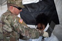U.S. Army Pfc. Daniel Schantin, assigned to 546th Area Support Medical Company places a neck brace on a role player in a simulated mass casualty decontamination medical triage tent at Travis County Exposition Center as part of Exercise Sudden Response 20.