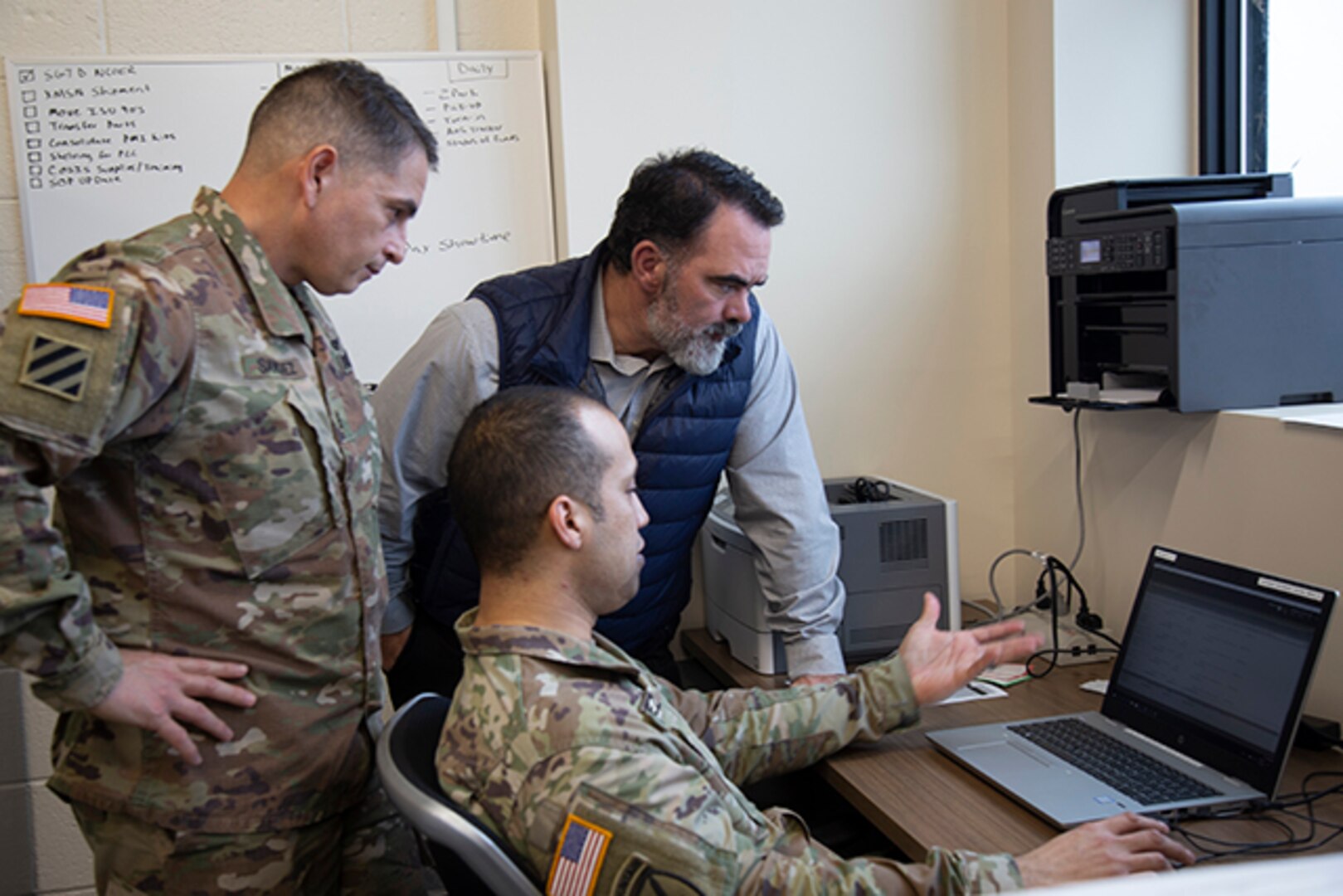 DLA Aviation team members review computer reports with Army service member.