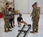 Maintenance chief talks about aircraft tow bar with DLA Aviation team members.
