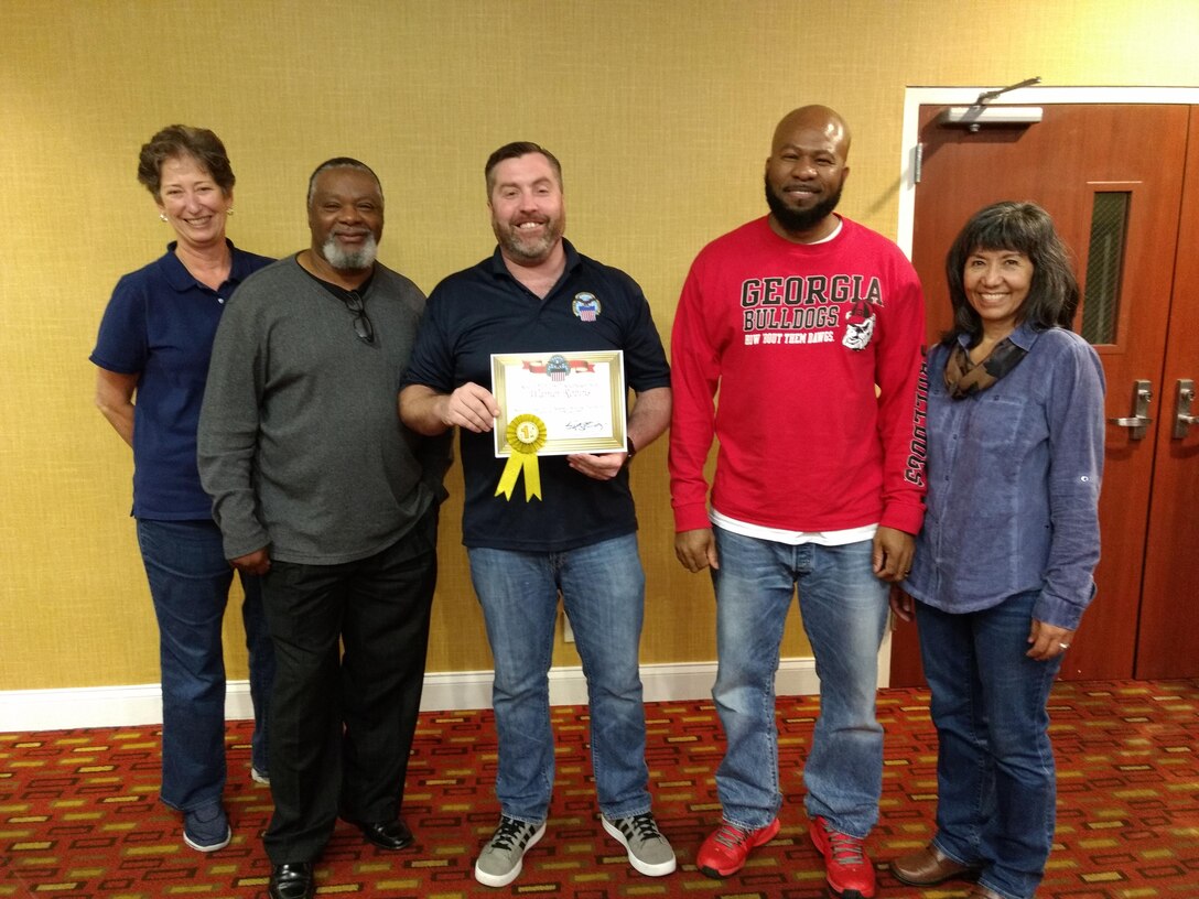 Warehouse Supervisor Willie Anderson (left center), Area Manager Mike Kelly (center) and Operations Supervisor Willie Mitchell (right center) accept the first place site award from South-East Deputy Director Audrey Weber (far left) and South-East Director Kathy Atkins-Nuñez (far right).
