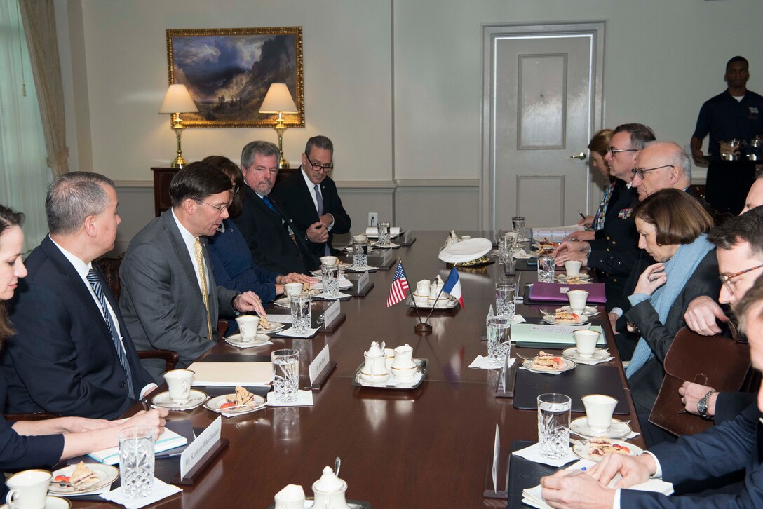 A dozen people meet around a large conference table.