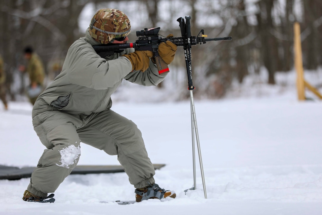 A soldier points a weapon while standing in snow.