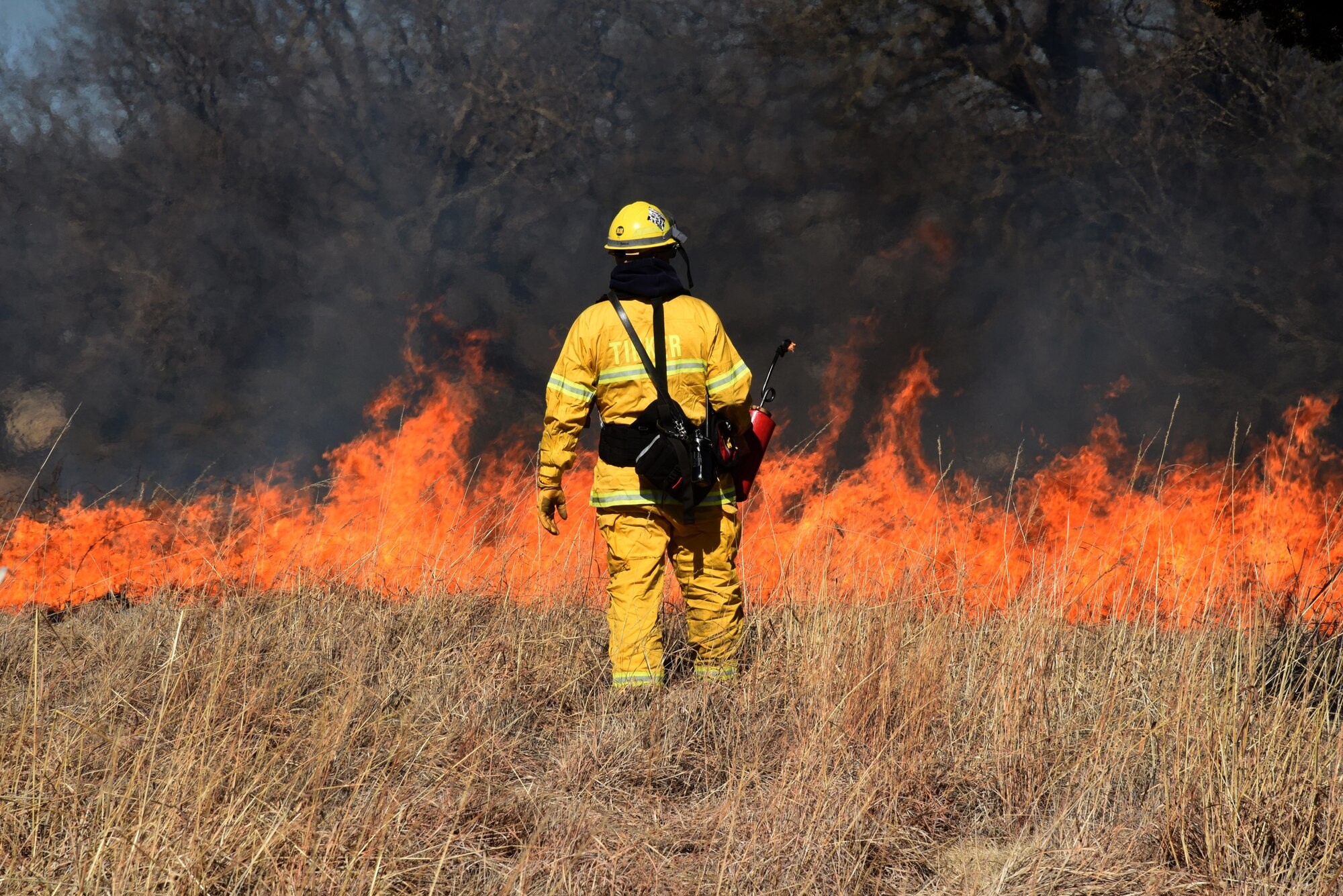 Lt. Michael Beane, with the Tinker Fire Department, carefully watches the flames in a prescribed burn close to base housing, lodging and the Tinker Club Mar. 6. Natural Resources and Tinker Fire Department personnel assisted a team from the Air Force Wildland Fire Branch in the prescribed burn. The burns eliminate invasive and non-native grasses and plants and act as a fertilizer, allowing new, productive growth in the Tinker grassland areas.