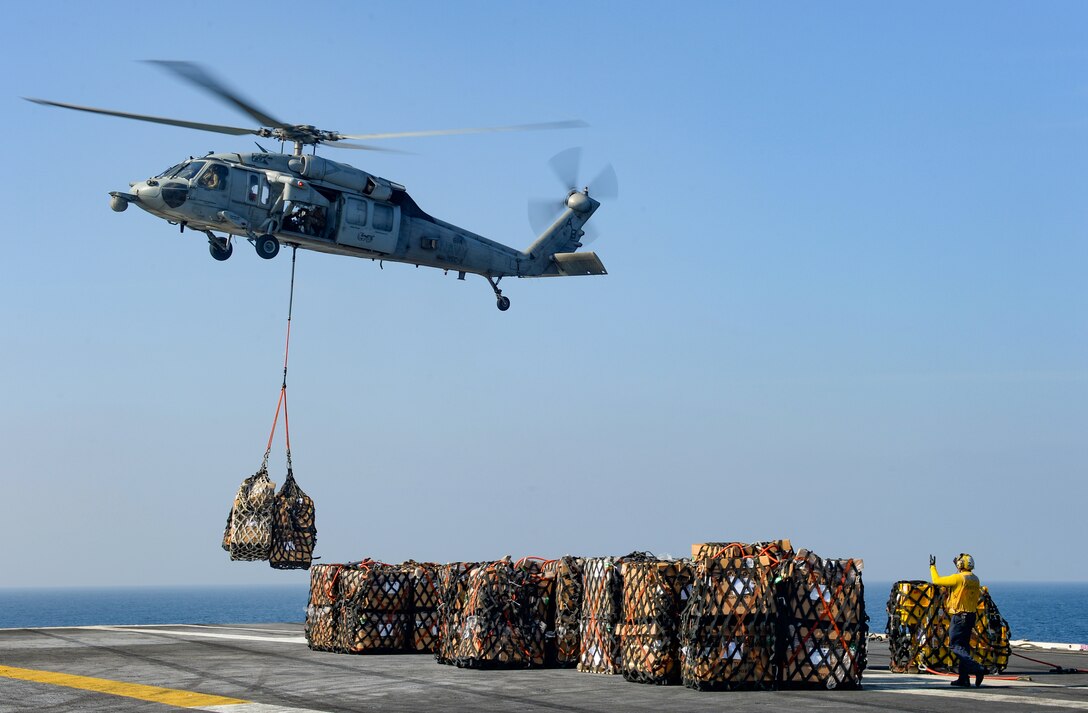 An aircraft drops loads of cargo onto a ship.