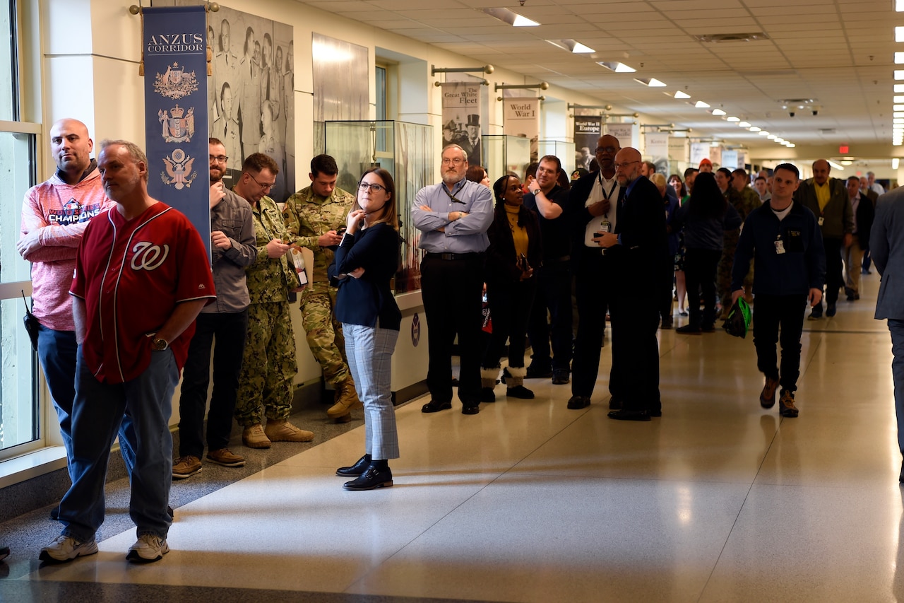 Civilians and military personnel line up in a hallway in the Pentagon.