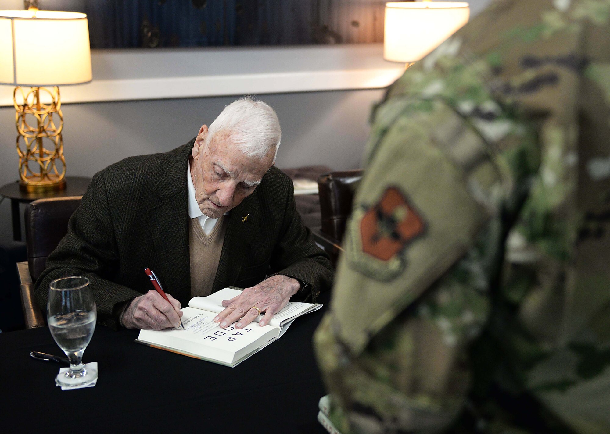 Retired Air Force Col. Carlyle “Smitty” Harris signs a book for an Airman during a book signing, Jan. 10, 2020 at the Columbus Event Center on Columbus Air Force Base, Miss. More than 130 books were signed by Smitty and his wife Louise for members of Team BLAZE. (U.S. Air Force photo by Airman 1st Class Hannah Bean)