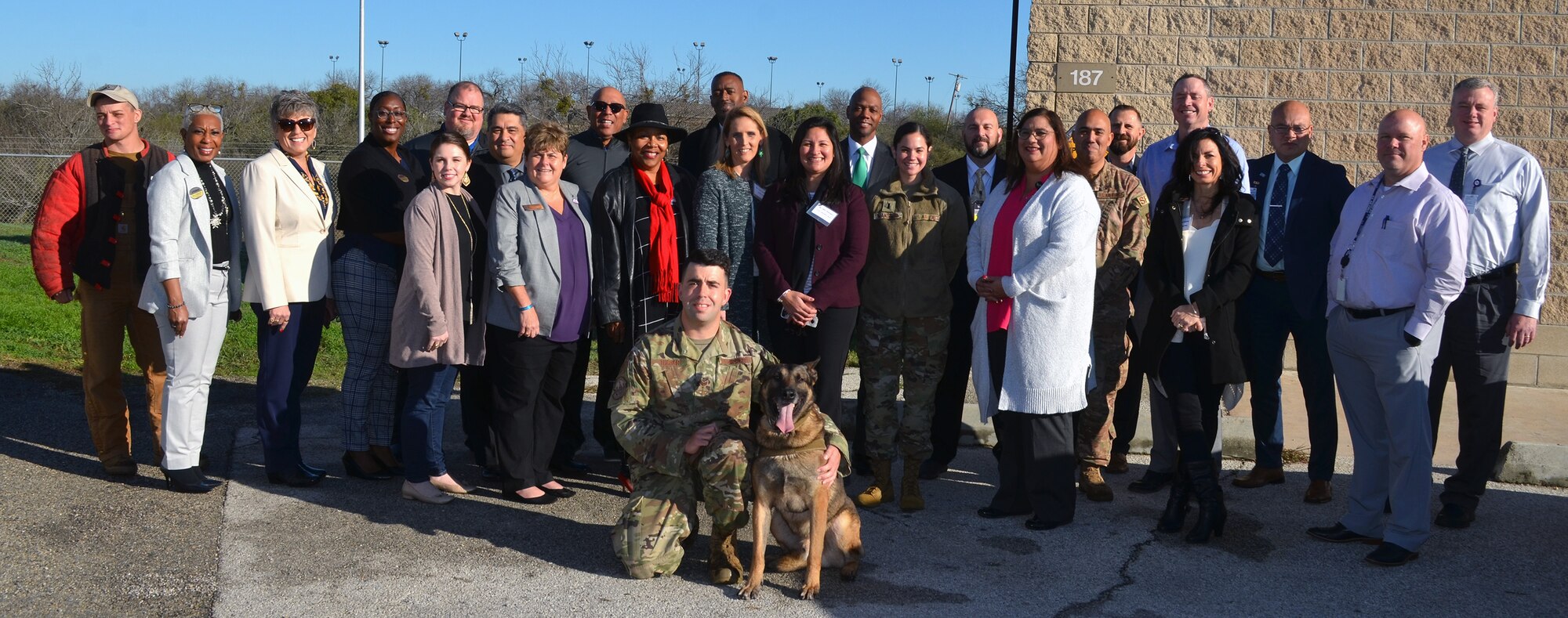 Military working dog Tarzan and his handler, Staff Sgt. Sean Tucker of the 802nd Security Forces Squadron, pose with a group of area school superintendents and administrators at Joint Base San Antonio-Lackland Annex Jan. 23. The group of 15 school superintendents and administrators, who were on a tour of JBSA-Lackland, got to see Tarzan perform in a military working dog demonstration.
