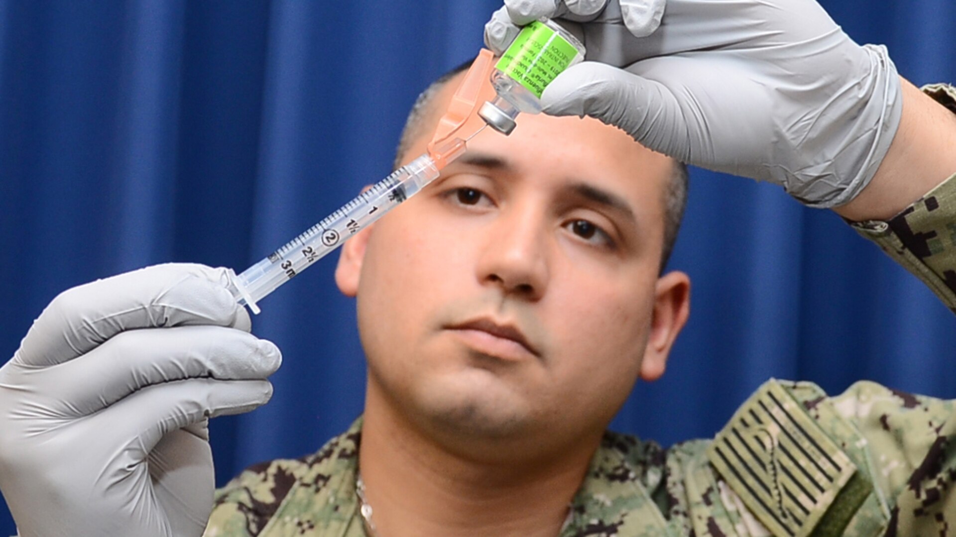 A man wearing gloves prepares a syringe with the influenza vaccine