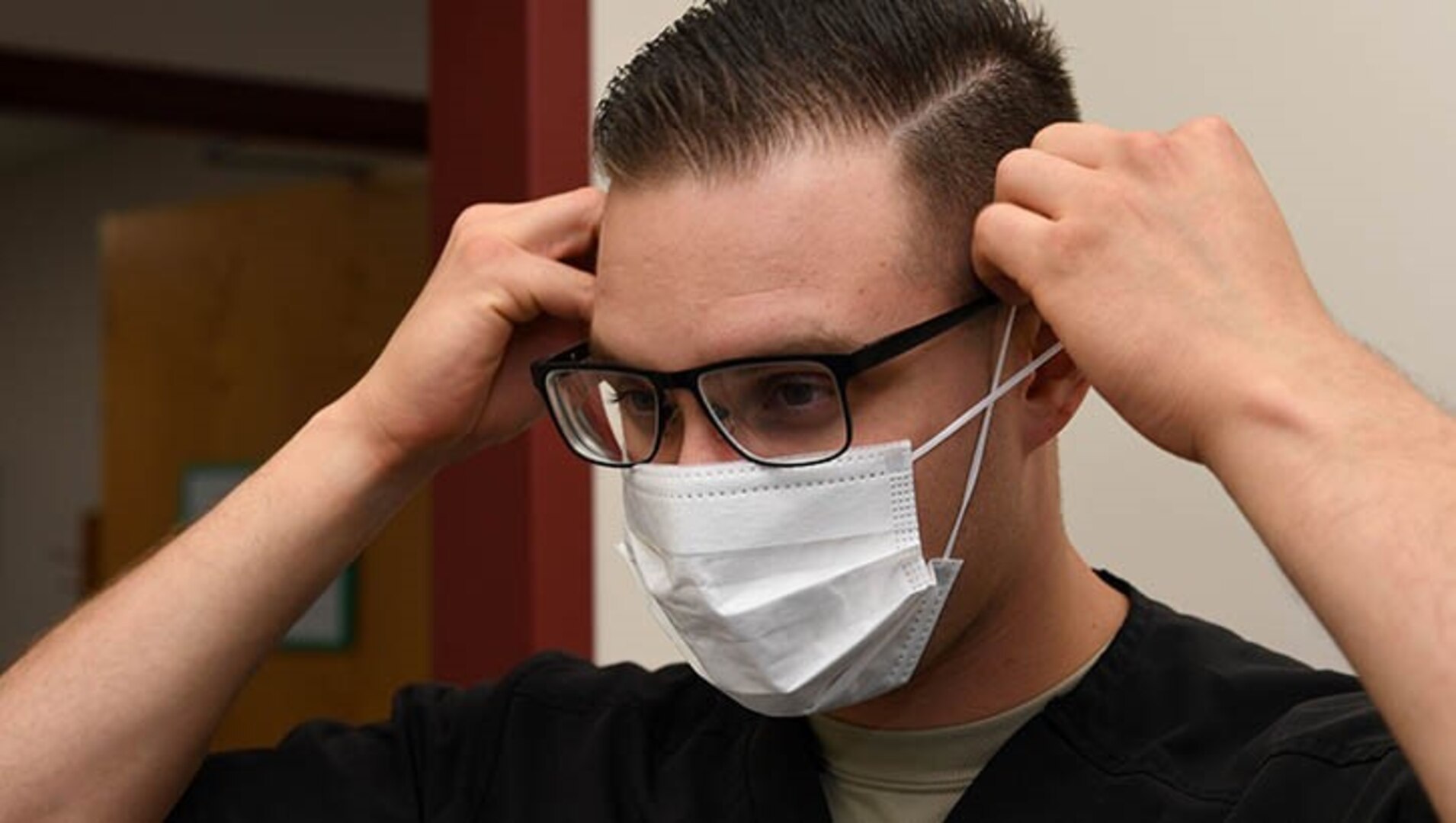 A dental assistant with the 319th Medical Group, demonstrates proper sanitary procedure by putting on a face mask at the medical treatment facility at Grand Forks Air Force Base, North Dakota.