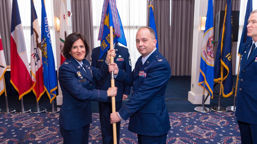 Col. Kathryn Brown, left, 11th Operations Group commander, places the guidon for The United States Air Force Band into the hands of Col. Don Schofield as he takes command of the unit in a ceremony at Joint Base Anacostia-Bolling, Washington D.C., on Jan. 15, 2019.