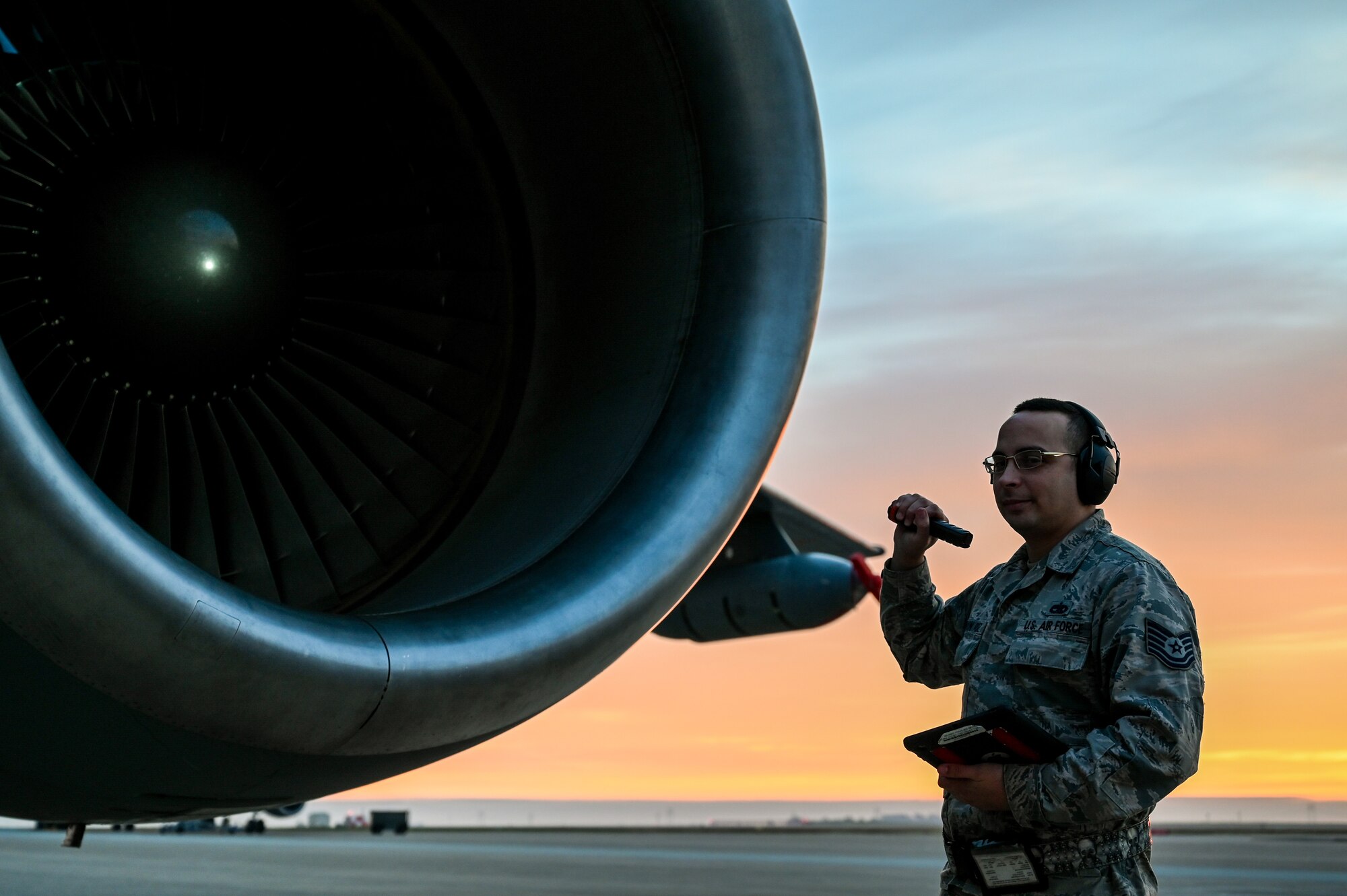 A photo of an Airman inspecting a jet turbine.