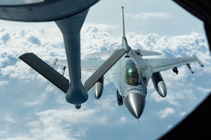 Fighter jet approaches tanker aircraft for aerial refueling.