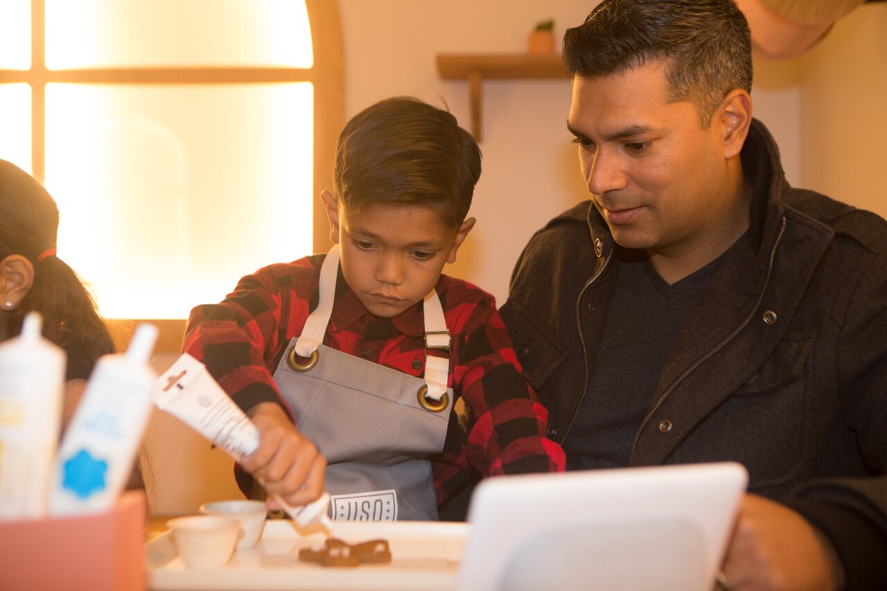 Man watches his son decorate with icing