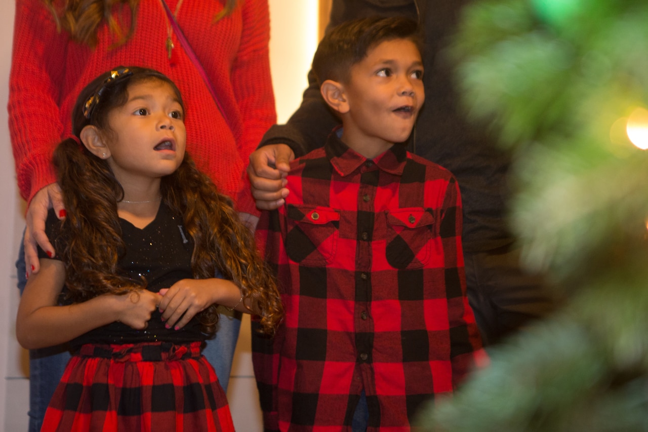 Young girl and boy looking at a Christmas tree