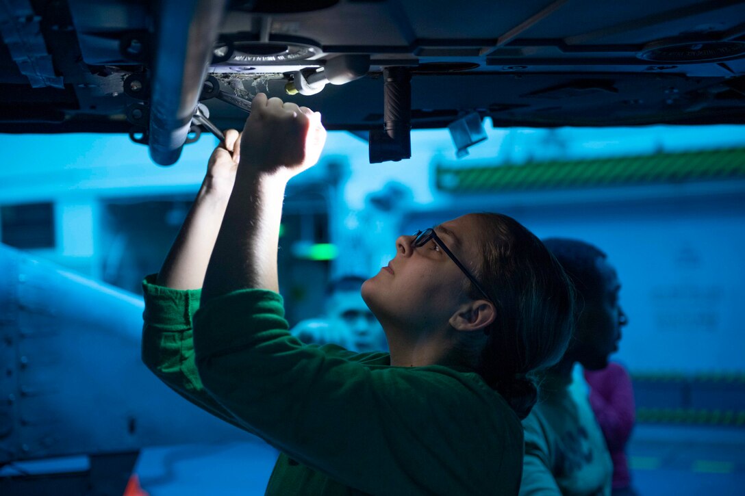 A sailor works on a helicopter.