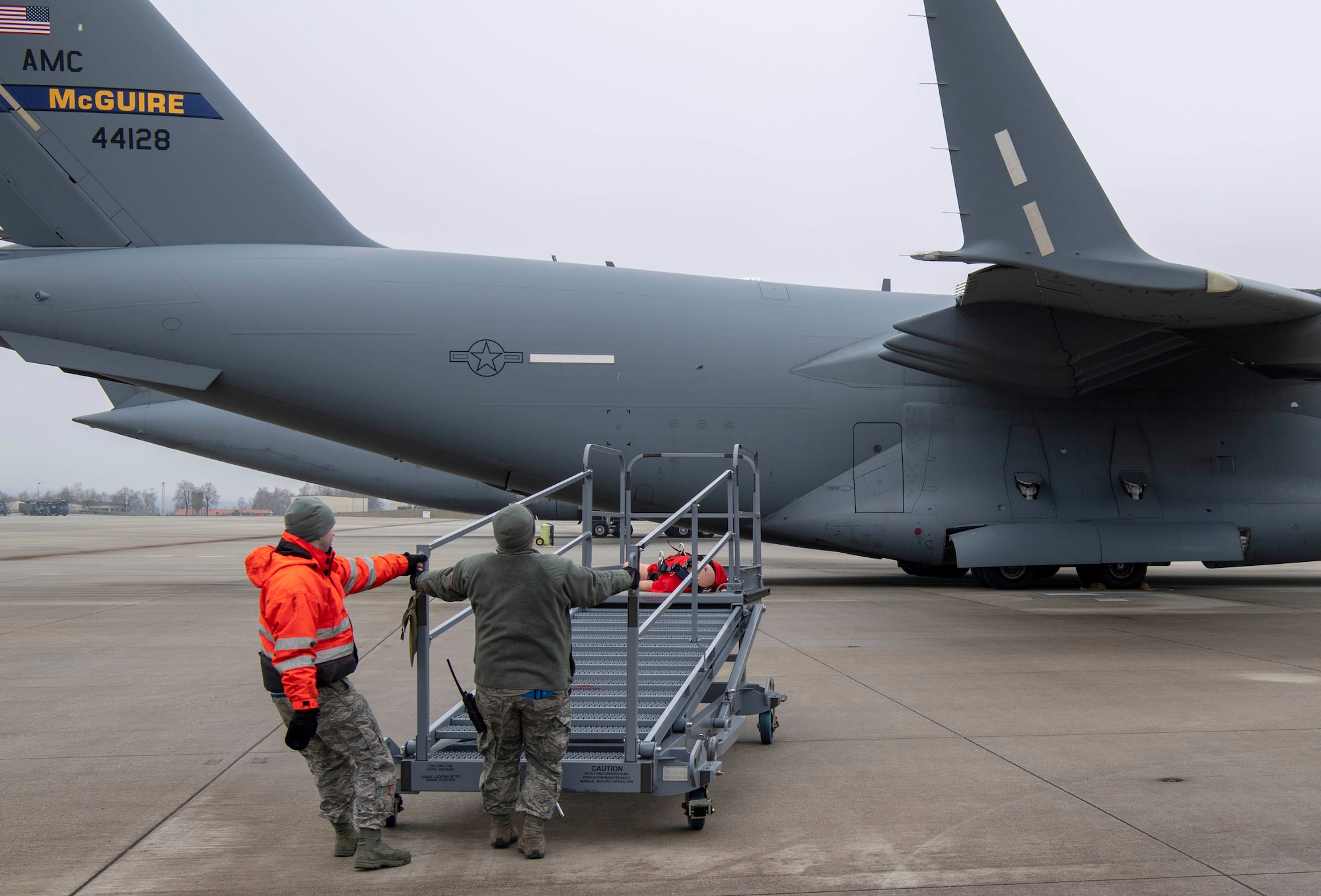 U.S. Air Force Staff Sgt. Michael Morrissey, 726th Air Mobility Squadron electrical and environmental systems craftsman, left, and Senior Airman Billy Meyer, C-17 instrument and flight control system journeyman, right, use an aircraft maintenance lift to move a training dummy during a fall protection exercise at Spangdahlem Air Base, Germany, Jan. 23, 2020. The Airmen completed the exercise as part of fall protection training that included the practical exercise, a computer based training and safety harness familiarization. (U.S. Air Force photo by Senior Airman Kyle Cope)