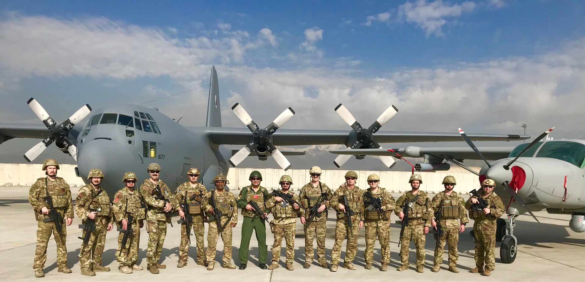 U.S. Air Force Lt. Col. Carl Miller, 538th Air Expeditionary Advisory Squadron commander, with members of his unit in front of an Afghan air force C-130 Hercules and AC-208 Combat Caravan on the flightline at Hamid Karzai International Airport in Kabul, Afghanistan in this undated photo. Miller was named a 2019 Lance P. Sijan United States Air Force Leadership Award winner in the senior officer category. (Courtesy Photo)